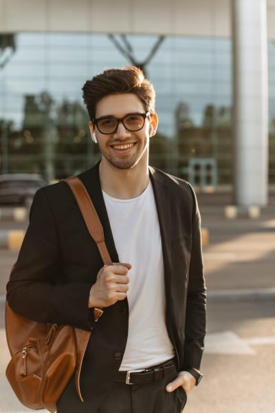 happy businessman in eyeglasses looks into camera and smiles sincerely brunette guy in black jacke.jpg